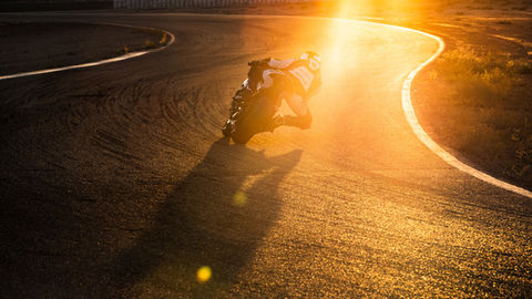 Motorcyclist speeding on track, sunset