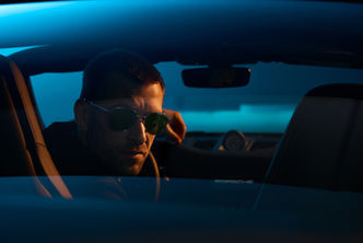 Man in sunglasses driving a car at night