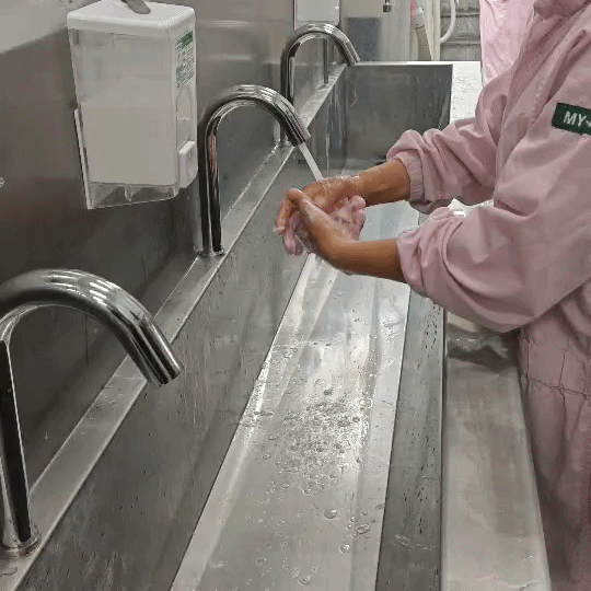 Factory workers wash their hands using automatic stainless steel faucets, adhering to GMP and HACCP standards, by Hygienic Corporation.