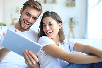 “Lovely couples seating in the living room watching streaming television on tablet”