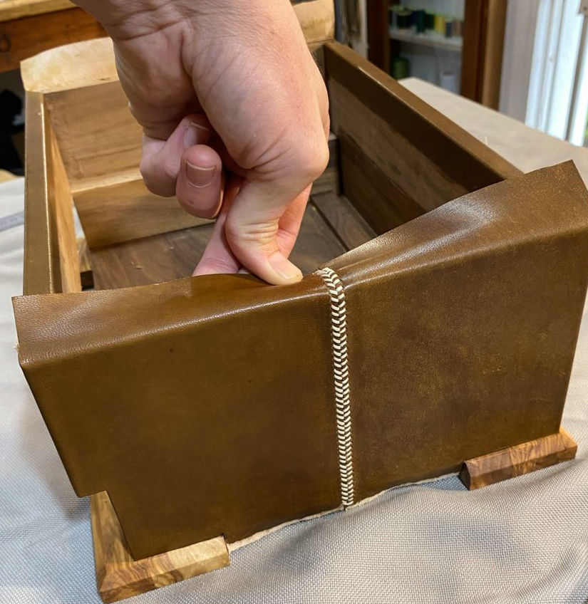 Here I wet and stretch out the leather, before gluing it down, so that it neatly takes the shape of the edge.