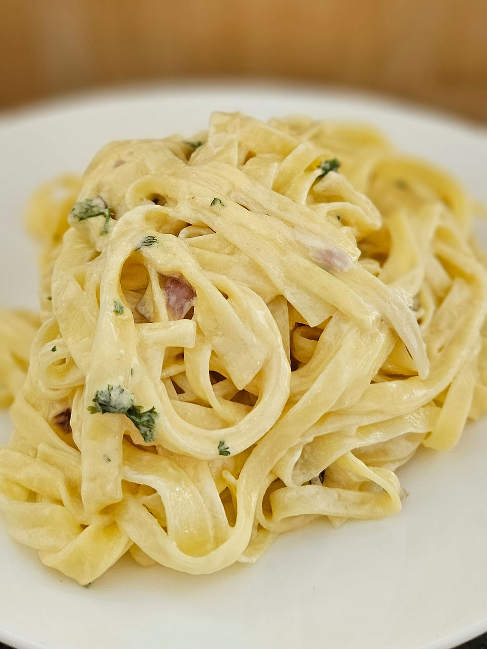 Cremige Filotea Fettuccine al Limone mit Parmigiano, Petersilie und feiner Zitronennote auf einem weissen Teller serviert.
