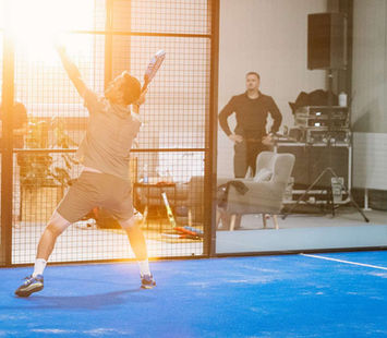 Padelspieler schlägt Ball vor Zuschauern