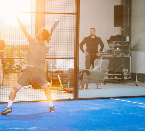 Padelspieler schlägt Ball vor Zuschauern
