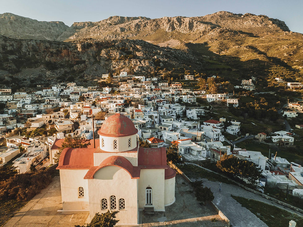 Classic Orthodox church in the foreground, backed by a quaint village against a mountainous backdrop