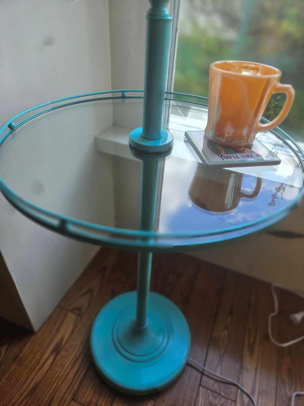 A closeup of the glass tabletop which is styled with a coaster and a vintage orange mug.
