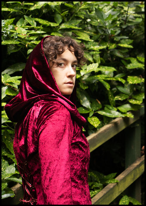 Indi in the red gown, looking over her right shoulder back at the camera