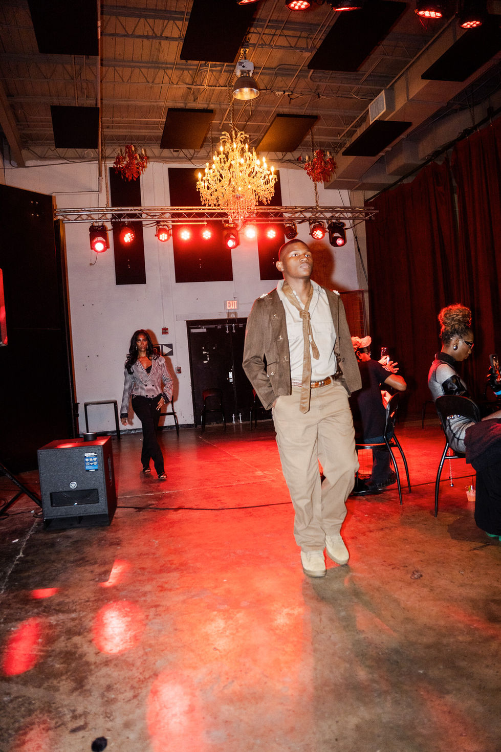 Male model walks a runway. Metamorphosis- WNTR '25 Debut Show. Red lighting ambiance