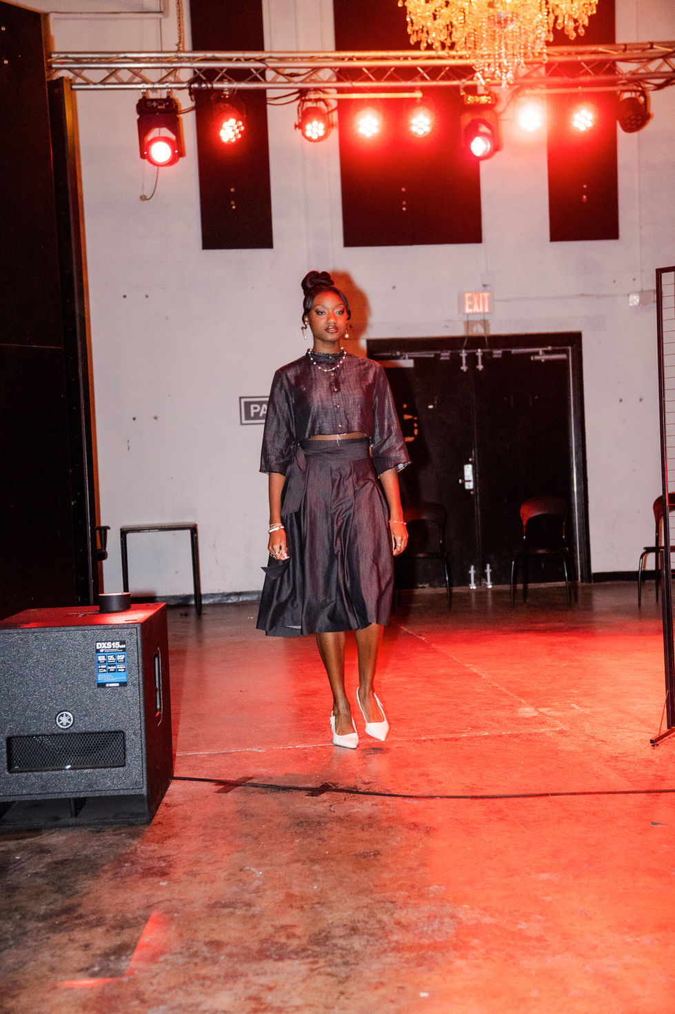Woman in navy blue outfit, standing on a stage, The Rebirth SS'26 fashion show.