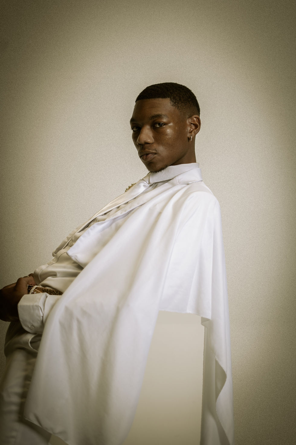 Young Black male model wearing white, posing for a fashion portrait.
