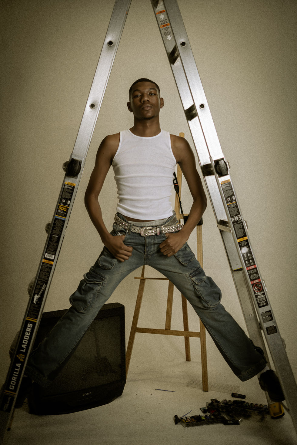 Young man posing confidently with a ladder in an artistic studio setting