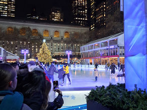 Ice skaters at Bryant Park Outdoor Rink at Night with a lit up Christmas Tree in the Background