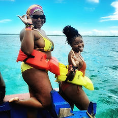 two girls in swimming suite, goggles, and safety jackets ready to dive in the turquoise waters of the Buccoo Reef