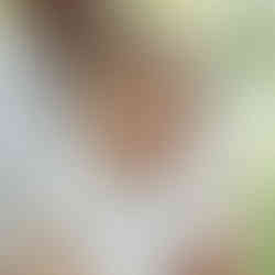 A close up of a smiling baby on her fathers lap during an outdoor family photoshoot in Manchester.