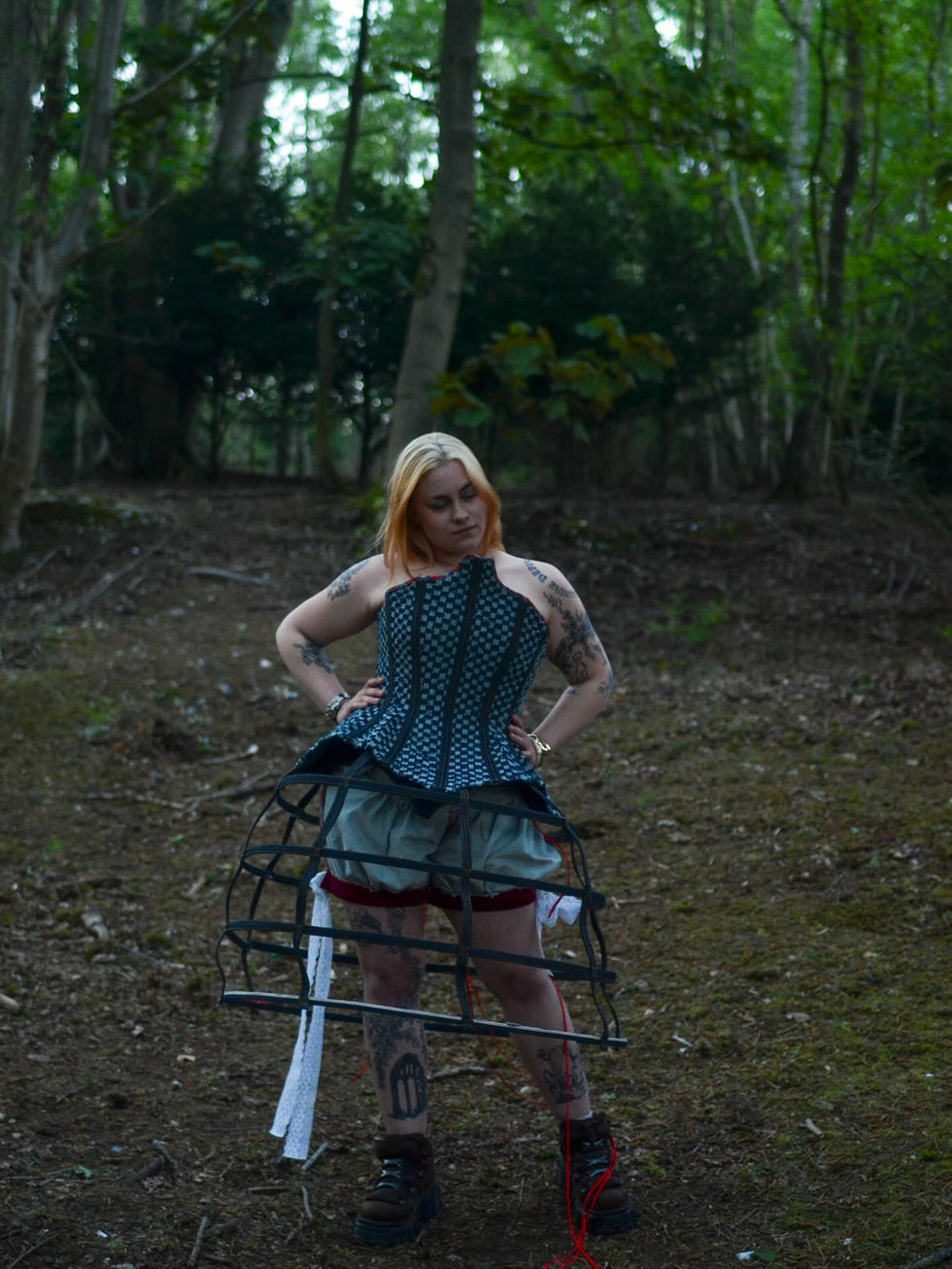 Person in teal corset and crinoline frame in forest