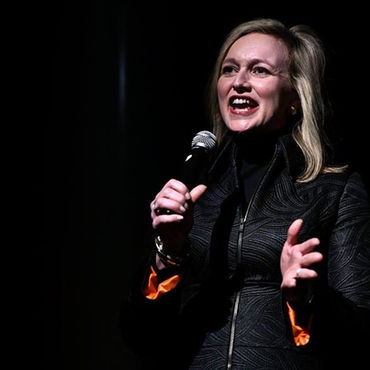 Photo of Laura Cox Kaplan with microphone at speaking engagement