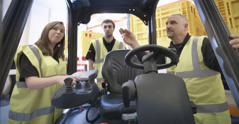 woman and 2 men looking inside a forklift