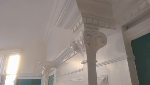 Architectural painting, white paint covering ornate carved wooden details.