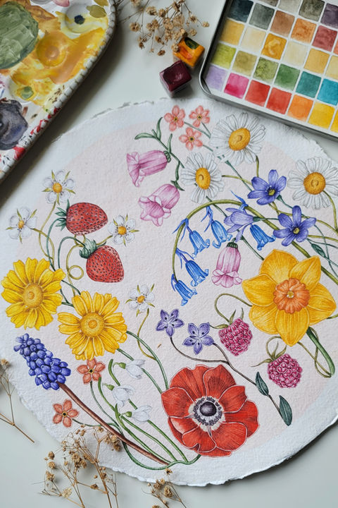 A beautiful watercolor painting featuring a circular arrangement of colorful flowers and berries, including yellow daisies, pink bell-shaped blooms, blue forget-me-nots, red poppies, and strawberries, on textured white paper. Surrounded by art supplies such as paintbrushes, watercolor paints, and dried plants, this vibrant floral artwork showcases a harmonious blend of nature and creativity.