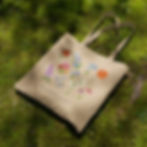 Beige eco-friendly tote bag featuring a charming botanical watercolor illustration of vibrant spring garden flowers