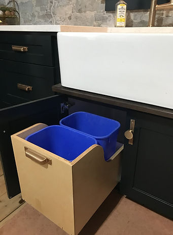 Custom Cabinetry Kitchen, dark green colour. Custom waste and recycling drawer that pulls out of the cabinet when it's open. Located below the skirt sink.