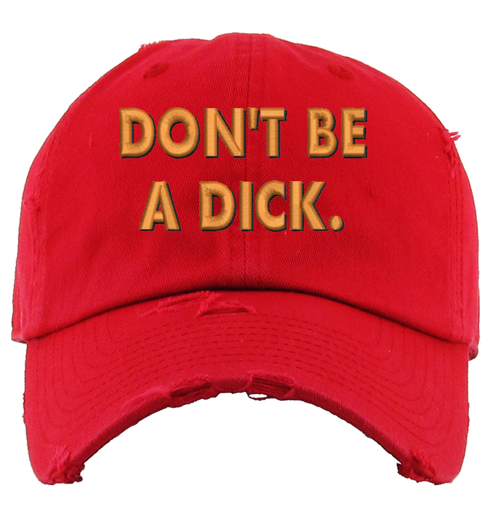 Red baseball cap with distressed fabric and the text 'Don't be a dick' in gold lettering.