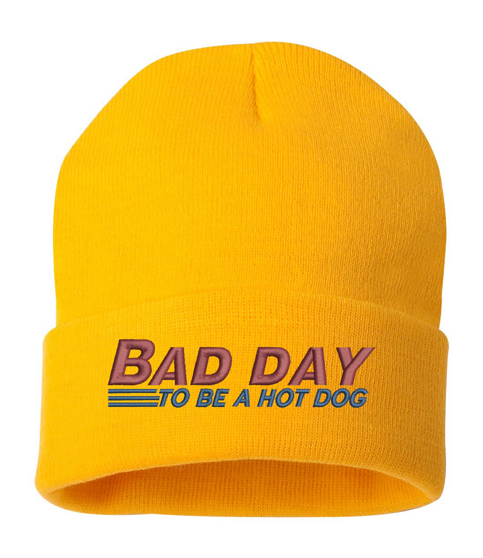 Yellow knit beanie with the text 'Bad Day To Be A Hot Dog' embroidered on it.
