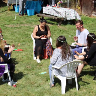 Group of people sitting and talking in a circle on the grass at Highams Lodge.