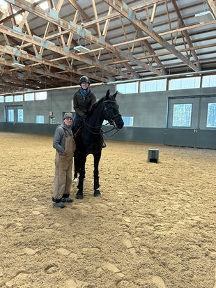 Two people pose with LENNOX in a dressage arena. Alison Famiglietti Dressage