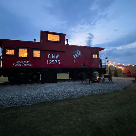 Red CNW 12575 caboose converted into a home at dusk