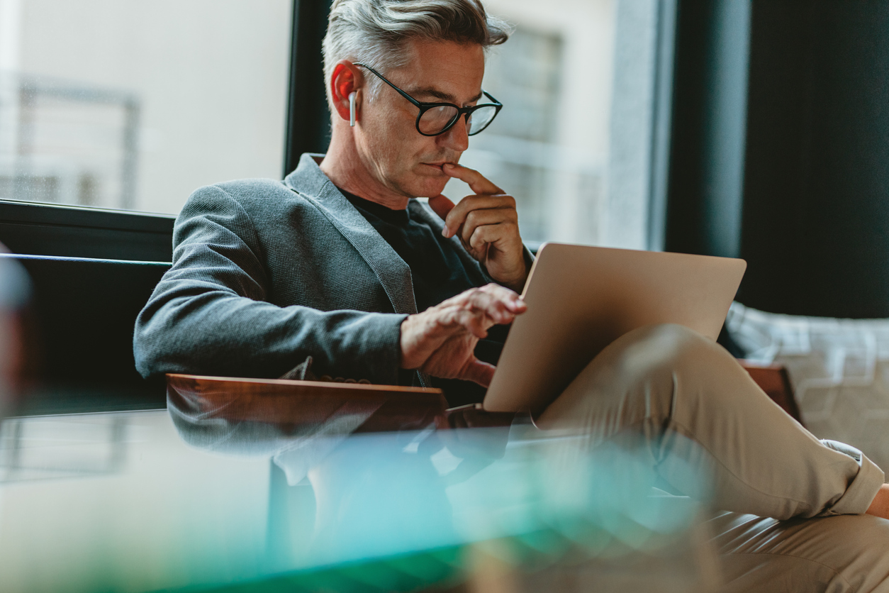 A man reading from his laptop whilst listening to music with Apple Airpods