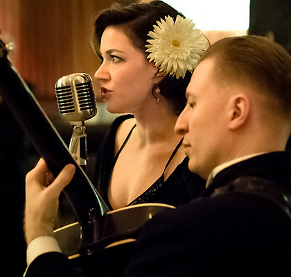 Glenn Crytzer with his guitar and Kim Hawkey looking glamourous at a Gatsby Party