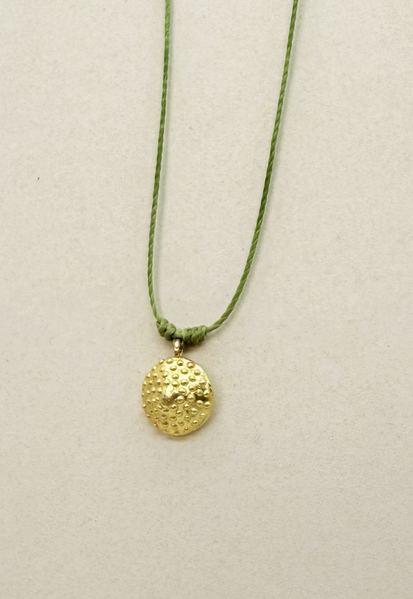Textured gold pendant on cord