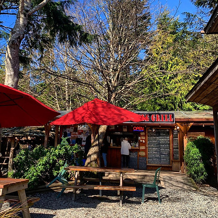red umbrella and picnic table in foreground, restaurant deck, menu, and ordering window in view