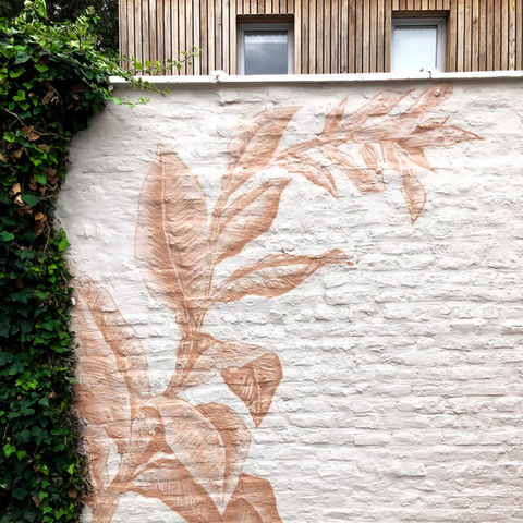 Décor mural végétal monochrome d'un plant de tabac peint sur un mur extérieur en pierre