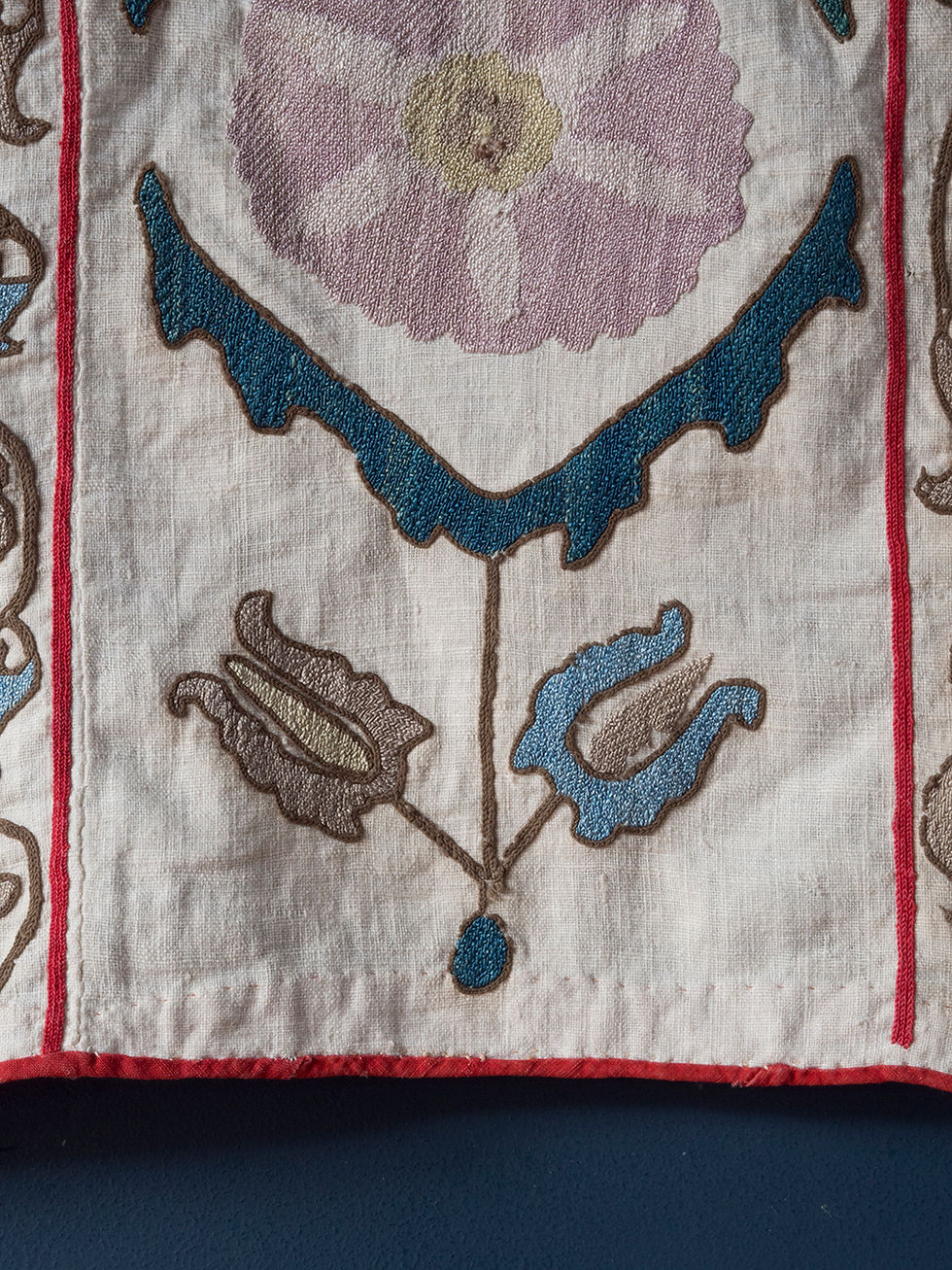 Thumbnail: early 20th century prayer suzani. Pink and green silk embroidered floral elements on a plain cotton field with a red border