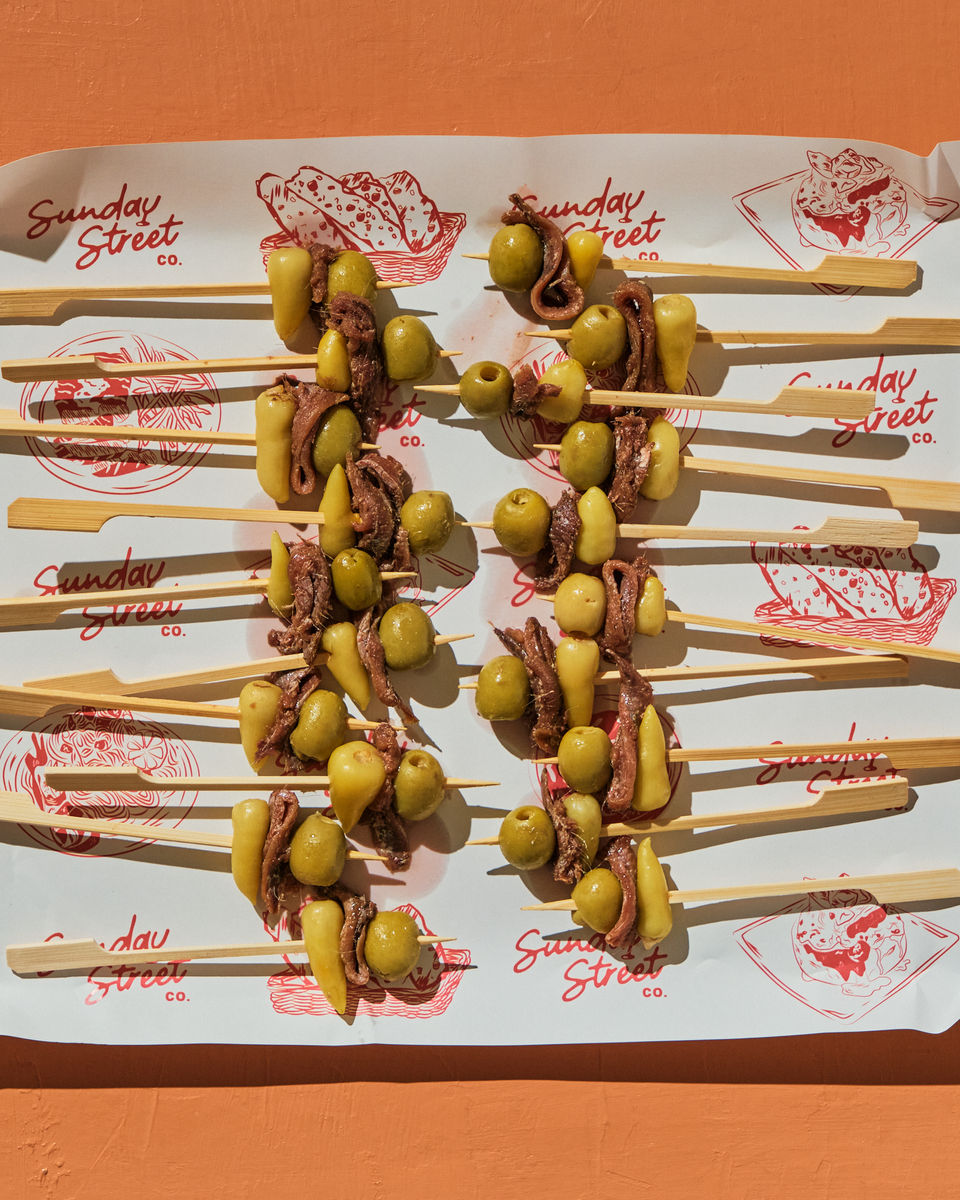 Anchovy, olive, and pepper skewers arranged on catering tray for appetizers