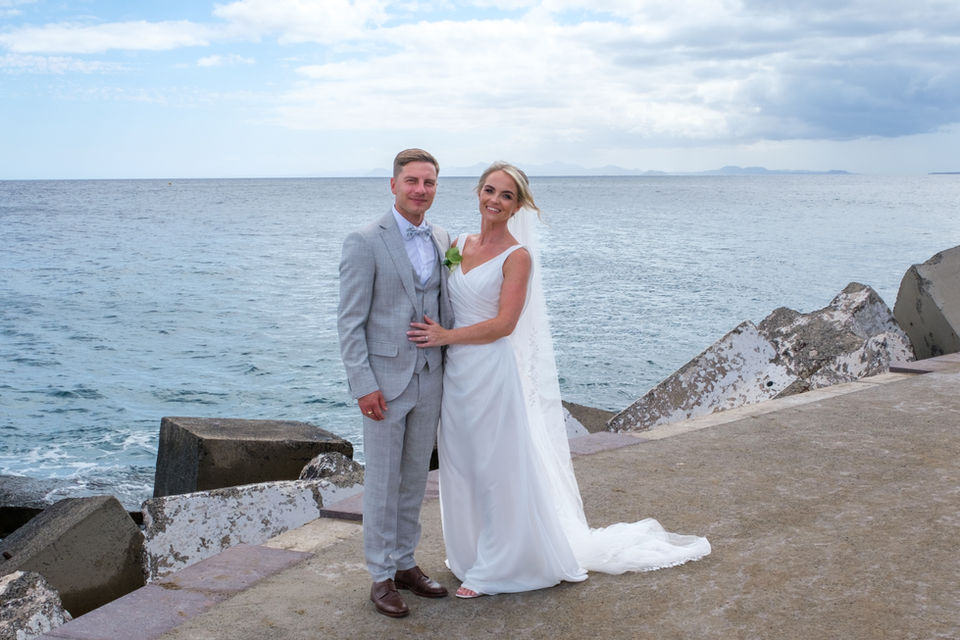 Bride and grooms walk along the the pier