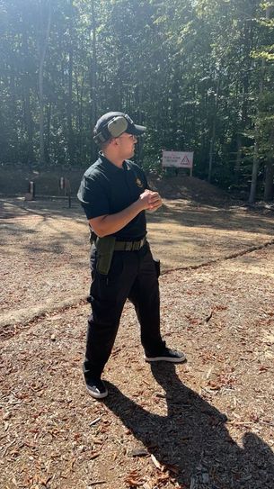 Instructor in tactical uniform briefing at outdoor shooting range