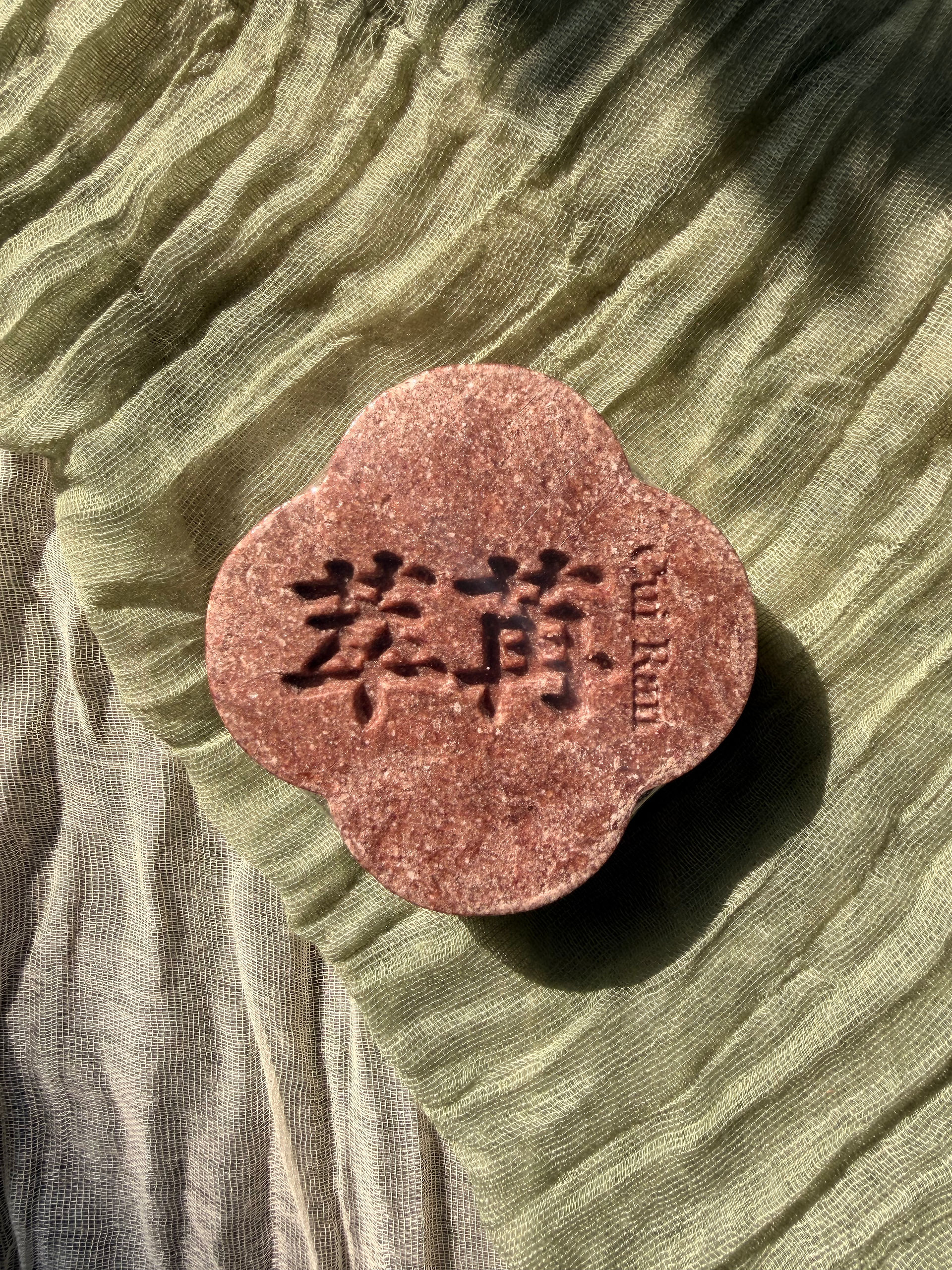 Real purple CUIRAN four-leaf-clover shampoo bar on textured fabric