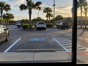 Strip center parking lot with painted stalls viewed from inside a vacant storefront