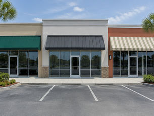 Three adjacent storefronts in a strip center with empty windows