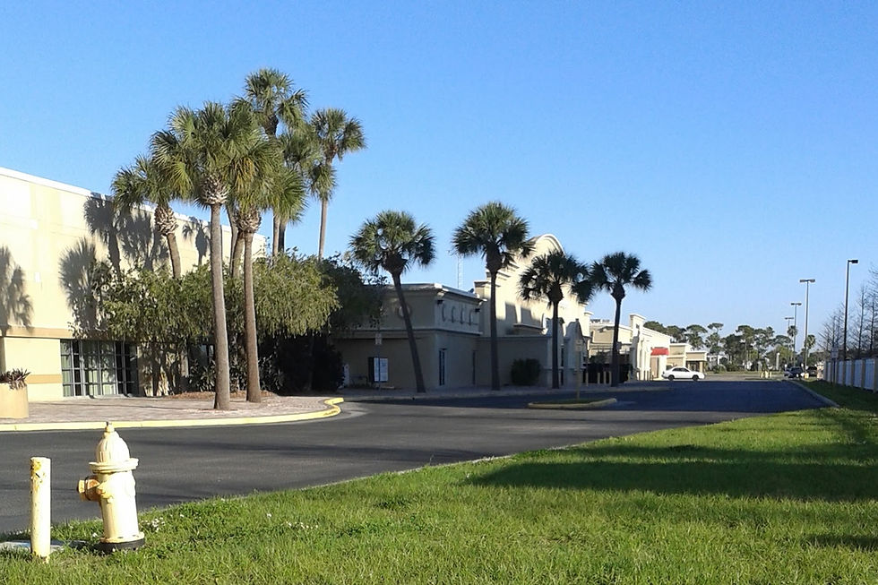 Retail strip center storefronts along a commercial corridor with parking lot in front