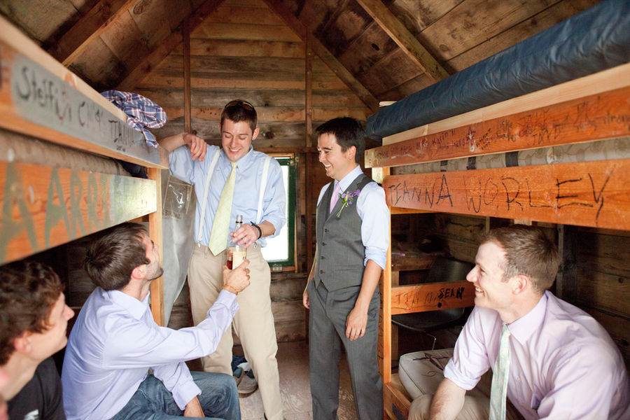 Groom and groomsmen relax in a rustic camper cabin.