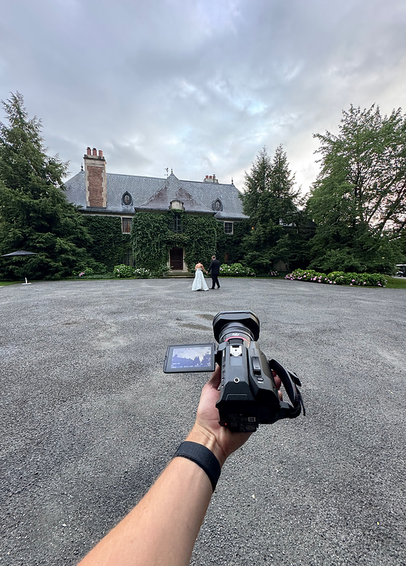 Wedding videographer filming bride and groom at outdoor wedding venue