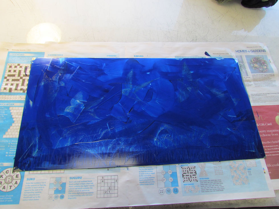 A metal plate covered in blue ink, lying on some newspaper