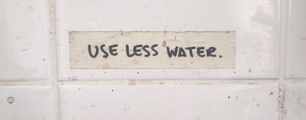A note on masking tape on white backsplash tiles that says "Use less water"