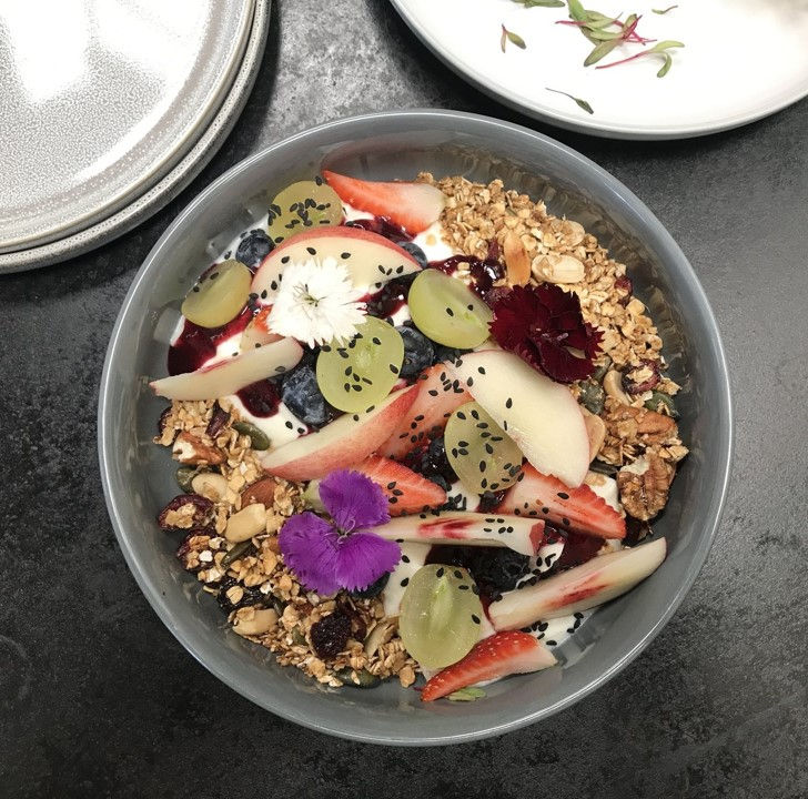 a bowl of granola with fruit and yogurt on a table
