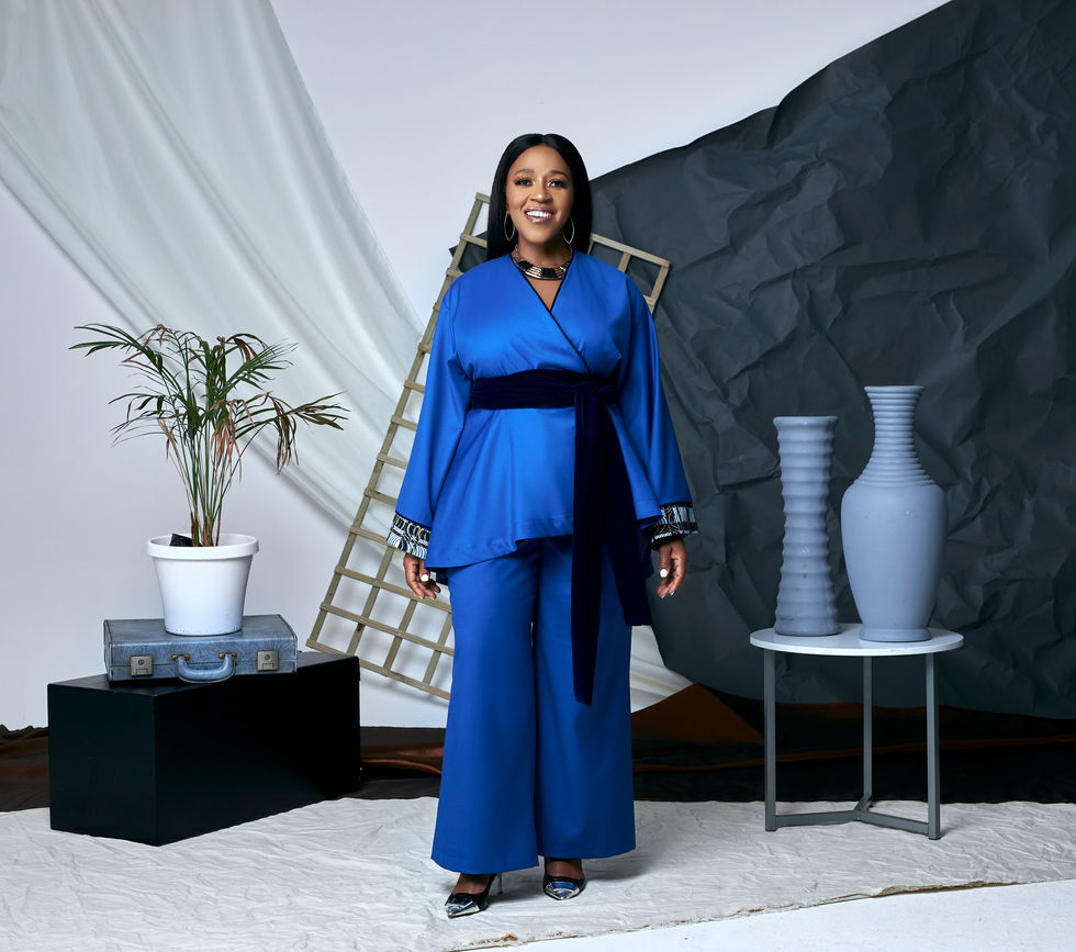 a woman in a blue suit stands in front of two vases
