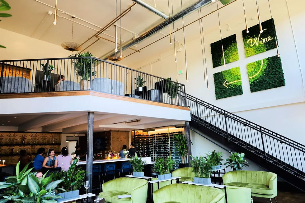 Two-level wine bar with lounge seating and greenery at Trellis Wine Bar in Denver